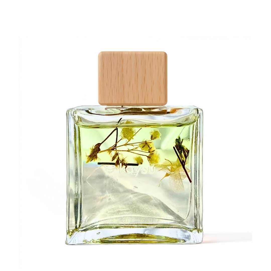 Clear glass perfume bottle with wooden cap and dried flowers inside on a white background