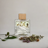 Perfume bottle with wooden cap and dried flowers on a light background