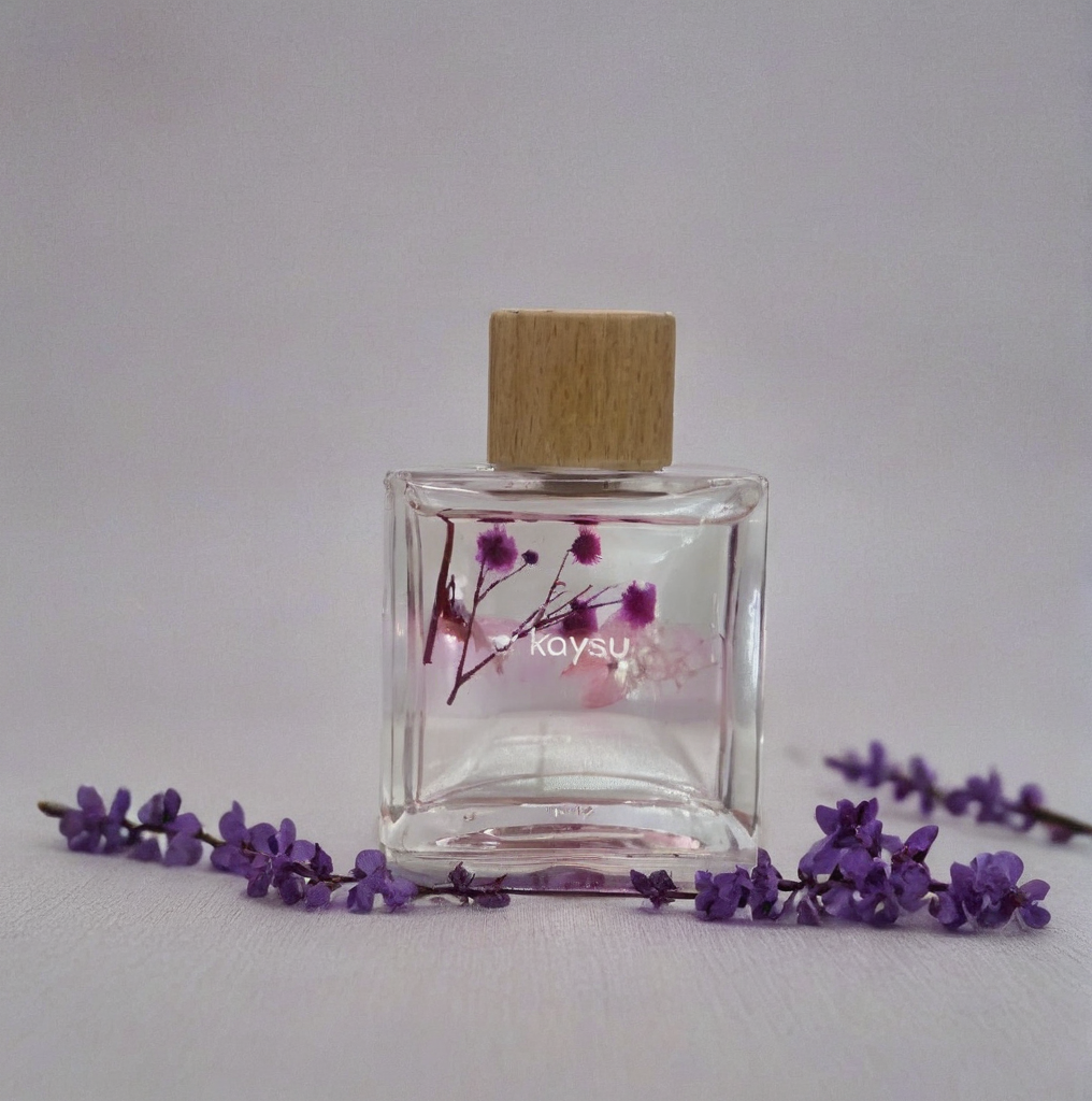 Clear perfume bottle with wooden cap and floral design on a light gray background