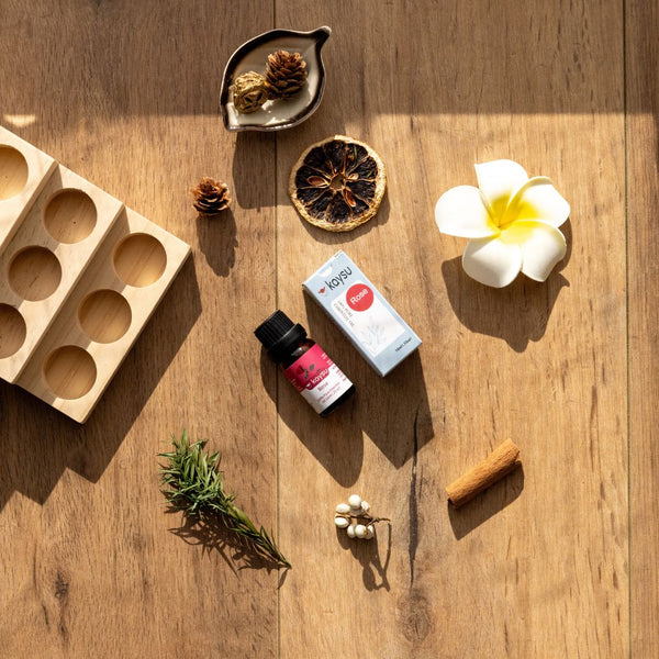 Collection of items including a wooden mold, bottle, box, flower, and herbs on a wooden surface.