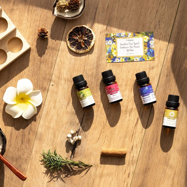 Essential oil bottles on a wooden surface with a flower and other items.