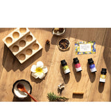 Essential oil bottles on a wooden surface with a flower and other items.