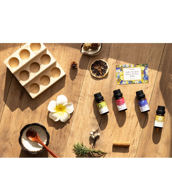 Essential oil bottles on a wooden surface with a flower and other items.